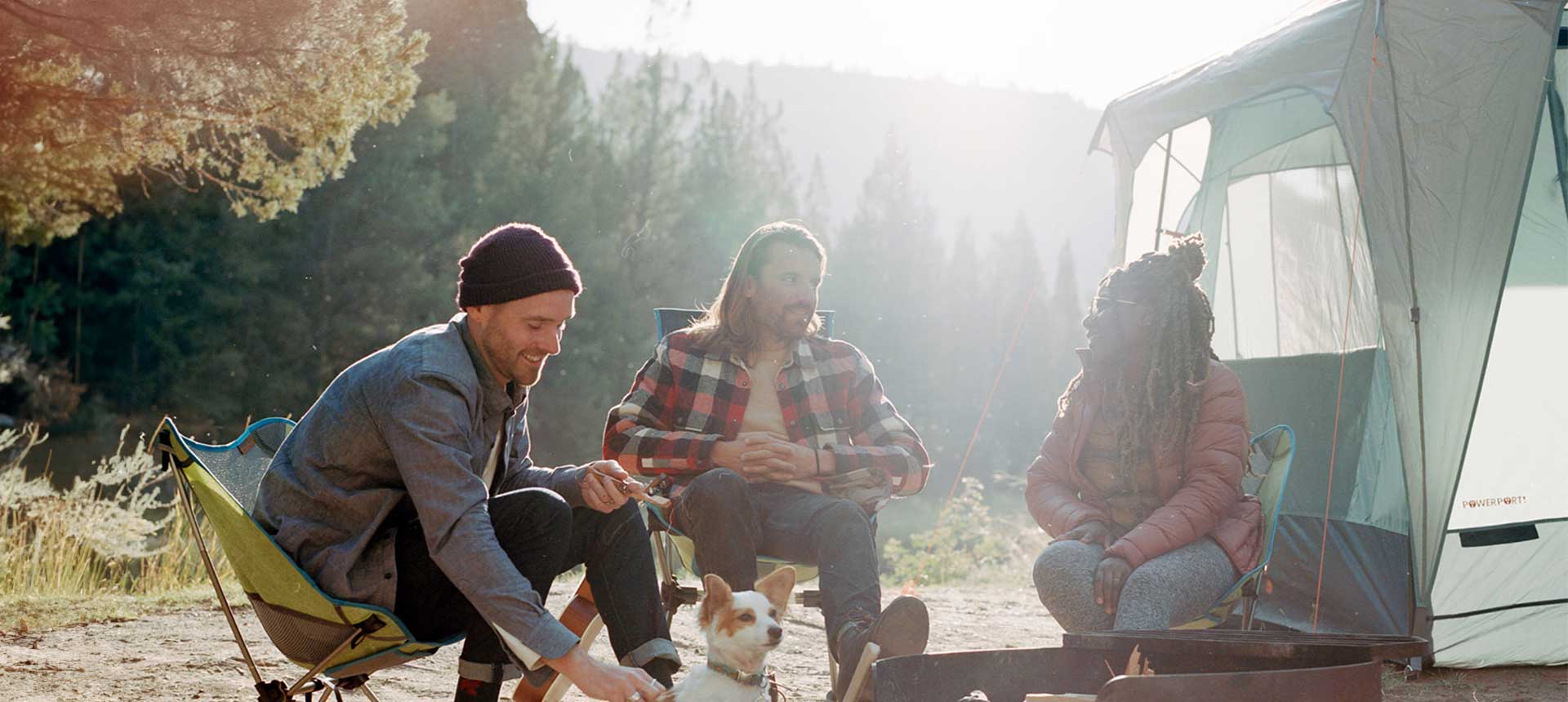 Three adults with small dog sitting in camp chairs next to text