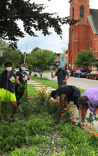 People in face masks gardening outside of a place of worship.