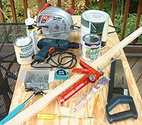 A collection of woodworking tools and materials is presented on a plywood table.